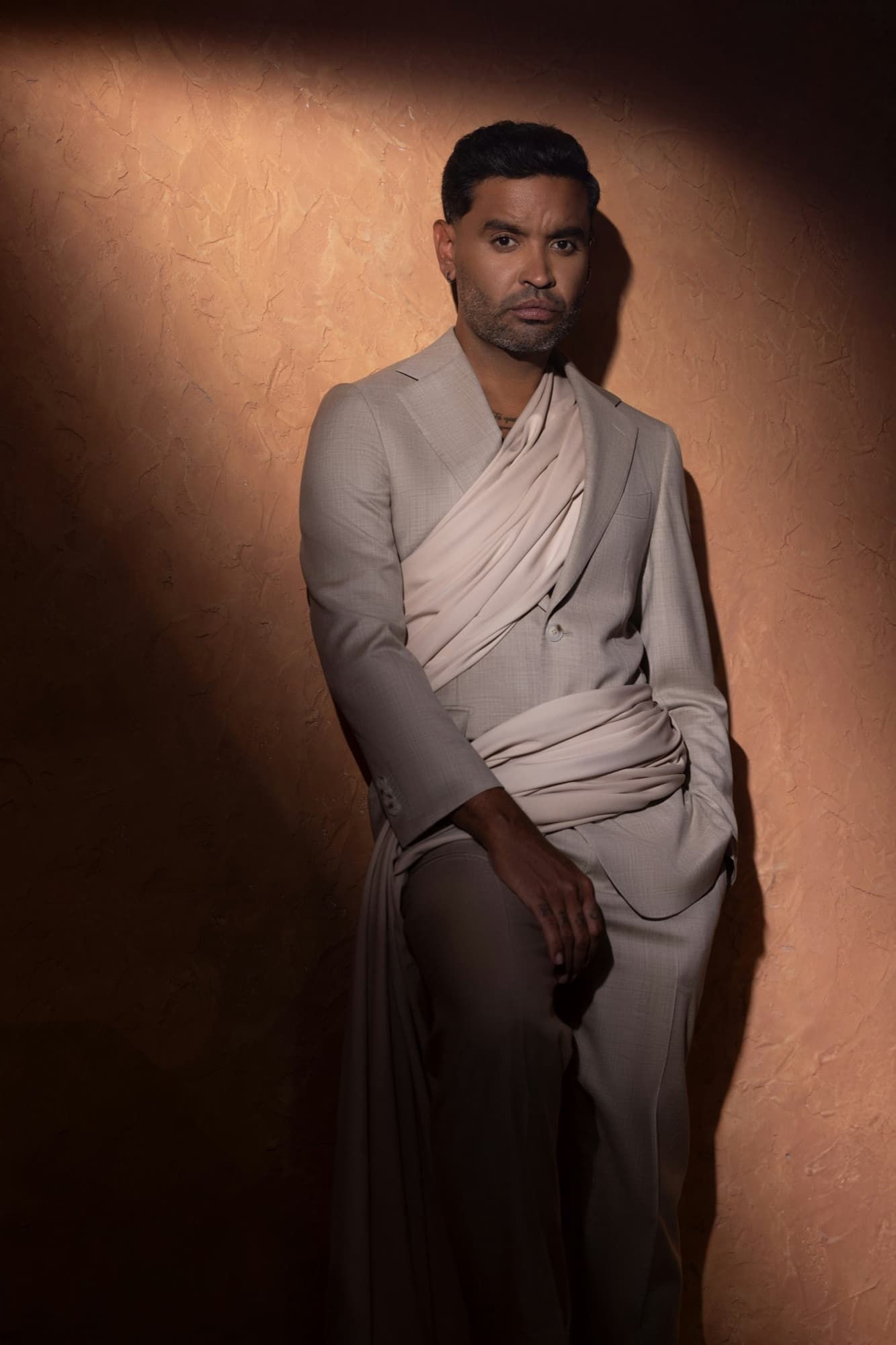 Zion in a sand suit wrapped with draped cloth — styled by Paloma Balvin